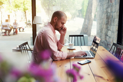 man with phone at laptop