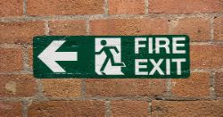 A fire exit sign against a brick wall