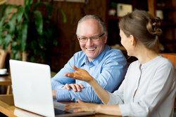 man and woman smiling at laptop