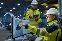 man and women in factory at monitors